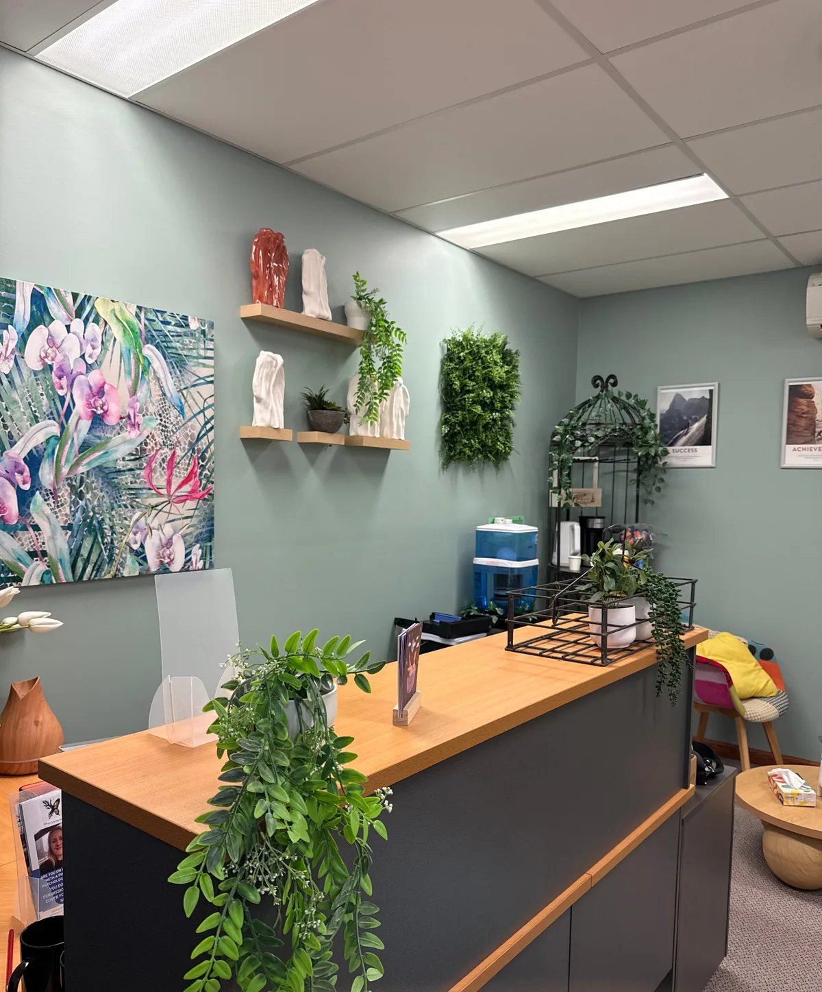 The Eclosia reception in North Lakes, with sage walls, plants and a watercolour orchid painting